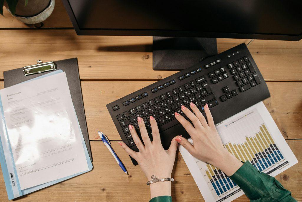 Persona teclando un teclado negro, con graficas a los lados
