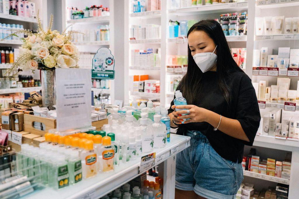 Mujer en una farmacia, leyendo sobre marketing para atraer clientes.