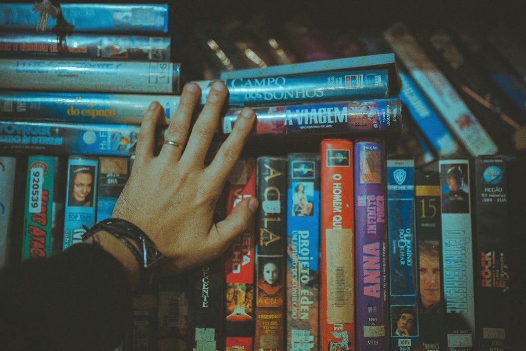Una persona tocando un estante lleno de DVDs