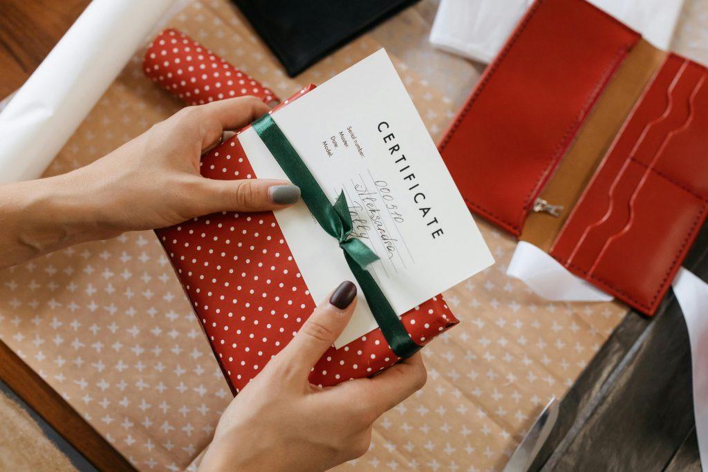 Persona recibe un certificado con un regalo color rojo