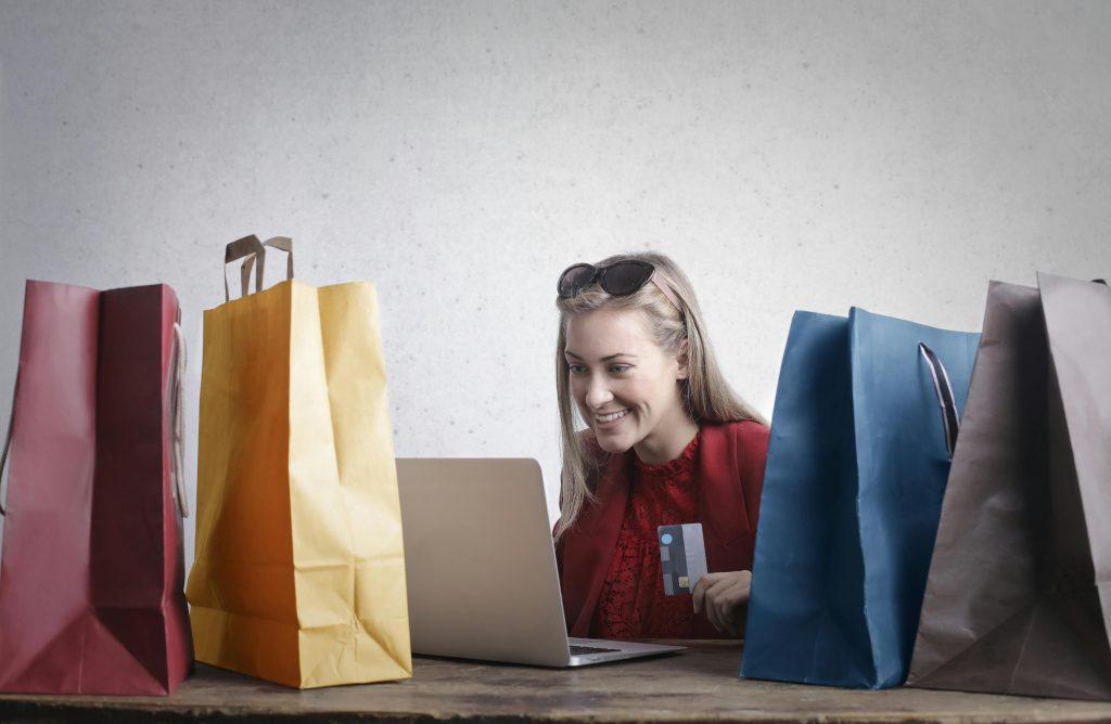 Una mujer feliz, rodeada de bolsas ya que a conseguido responder a la pregunta de como crear mi tienda online.