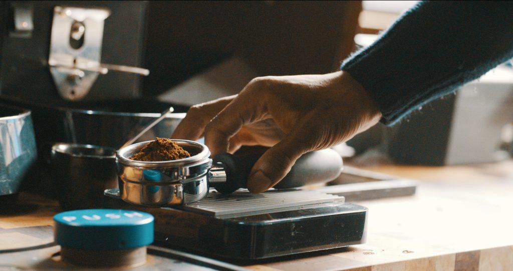 Un hombre poniendo café a una máquina expendedora de cafe en una empresa.