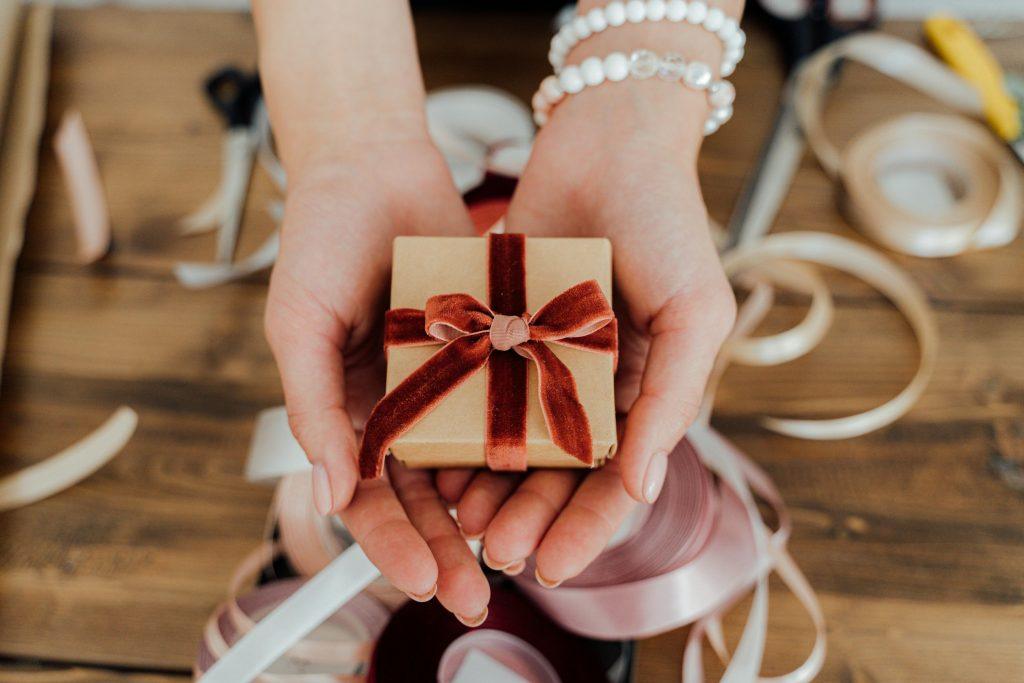 Una mujer, entregando un regalo pequeño para desear suerte por una nueva casa.
