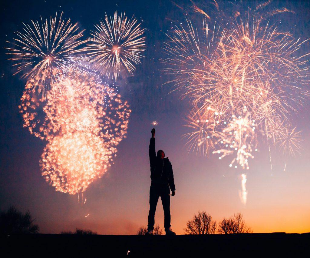 Un hombre celebrando las fallas, rodeado de fuegos artificiales de noche.