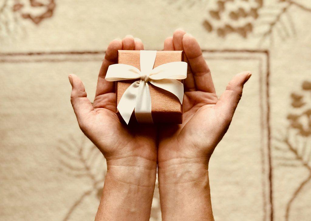 Imagen de dos manos cogiendo un regalo pequeñito.