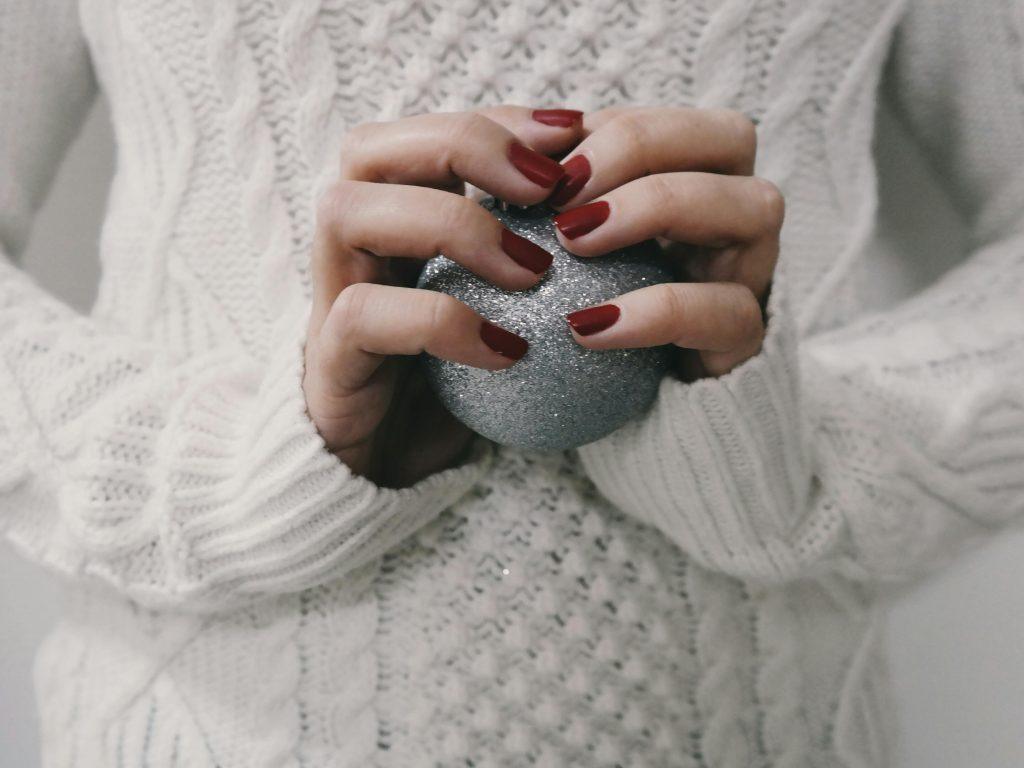 Chica con uñas rojo carmesí, sujetando una bola antiestres