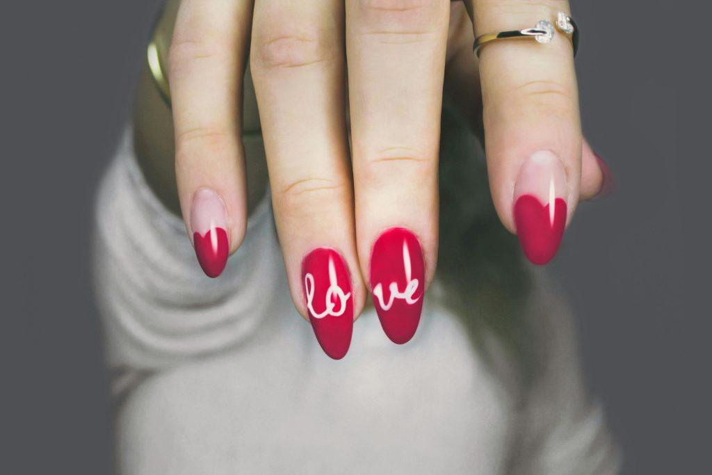 Mujer enseñando sus uñas en primer plano, estando contenta por haber encontrado el nombre correcto para la manicura y pedicura
