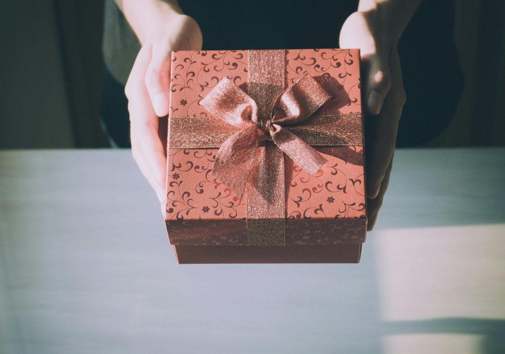 Una mujer sujetando con sus dos manos un regalo para su amiga enfermera