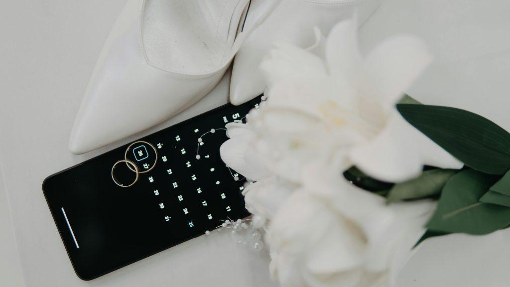 Un teléfono con unas flores blancas en una mesa, con las fechas de la boda y la planificación de los regalos para los invitados