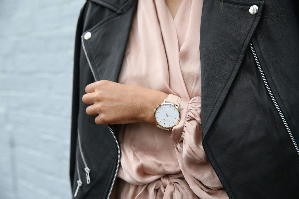 Una mujer, mostrando un reloj comprado en Vinted, con una chaqueta de color negro
