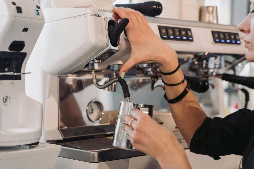 Mujer poniendo café en una taza metálica.
