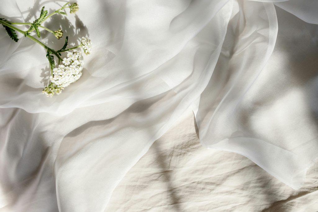 Tela blanca en una mesa blanca, con unas flores blancas
