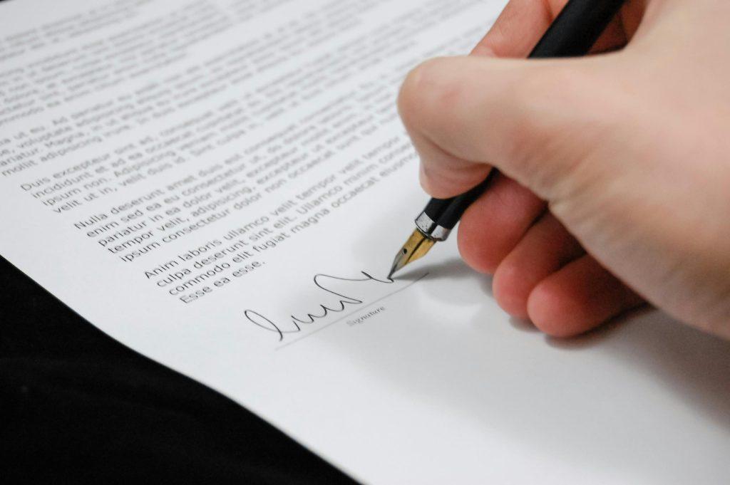 Una persona firmando la solicitud de la oepm para registrar su marca de ropa facilmente