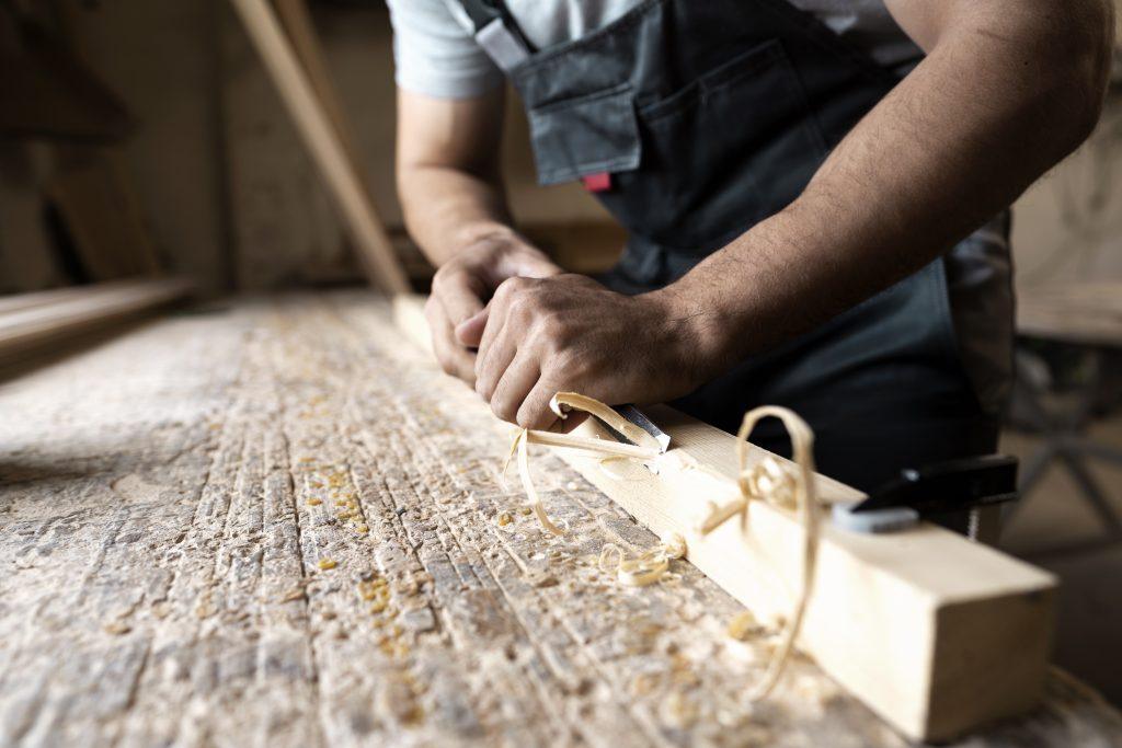 Una persona trabajando la madera de forma detallada usando herramientas indispensables