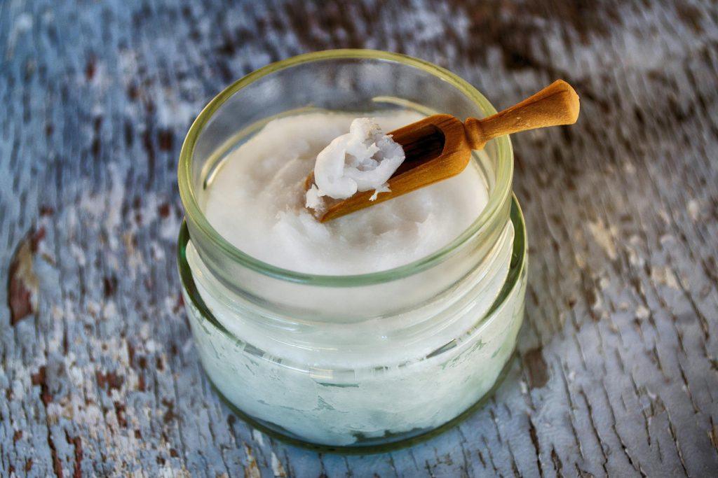 Una imagen de un cuenco con aceite de coco, que va a ser aplicado en el cabello seco y maltratado de una persona.
