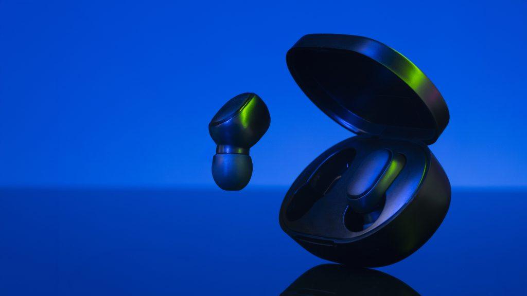 Una imagen de producto de unos auriculares pequeños y compactos en un fondo azulado
