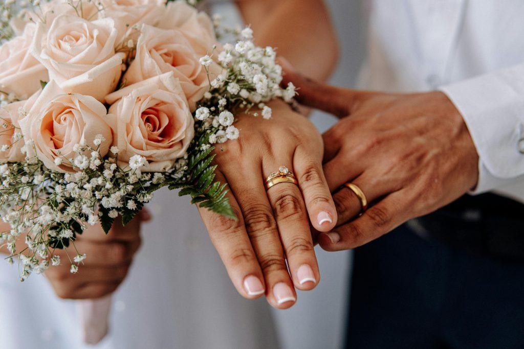 Una pareja enseñando sus manos con sus alianzas de oro en su aniversario de boda.
