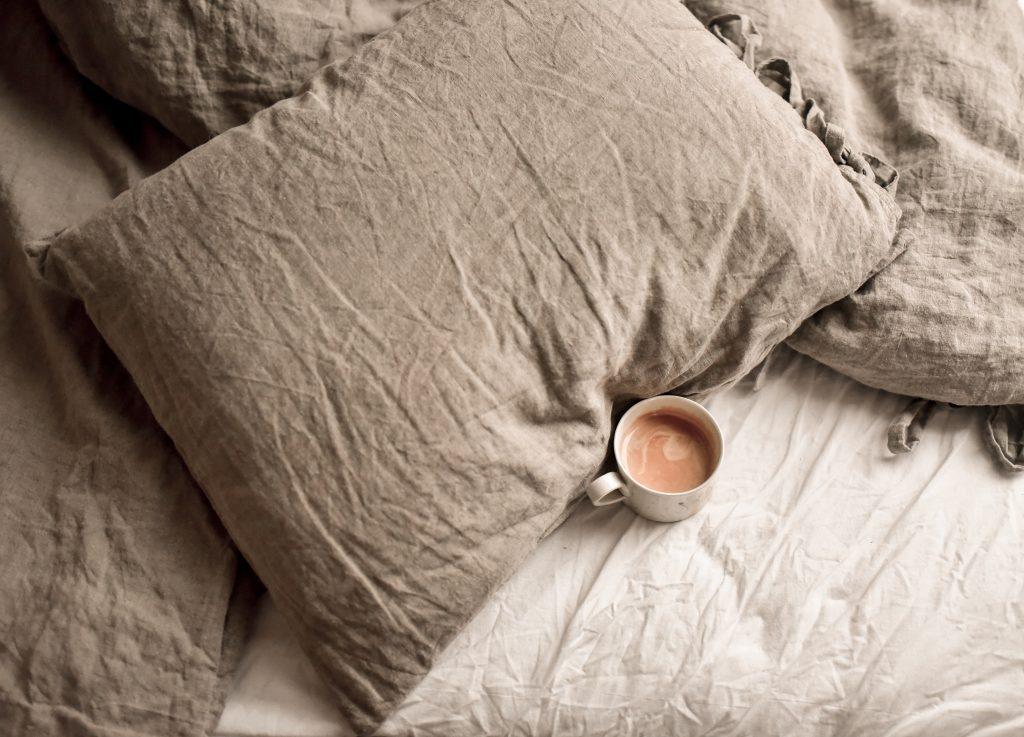 Una gran cama de matrimonio con una taza de café encima