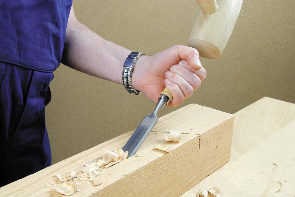Un hombre usando una de las mejores herramientas, el formón, para trata la madera con precisión con madera.