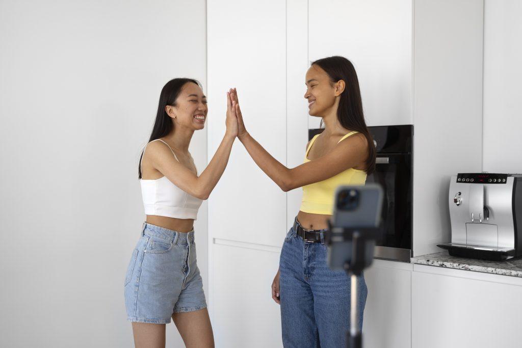 Dos chicas chocándose las manos en una cocina blanca
