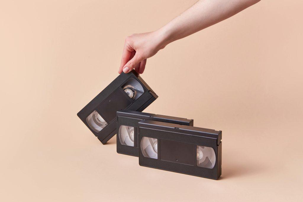 Una persona colocando en fina 3 películas VHS.