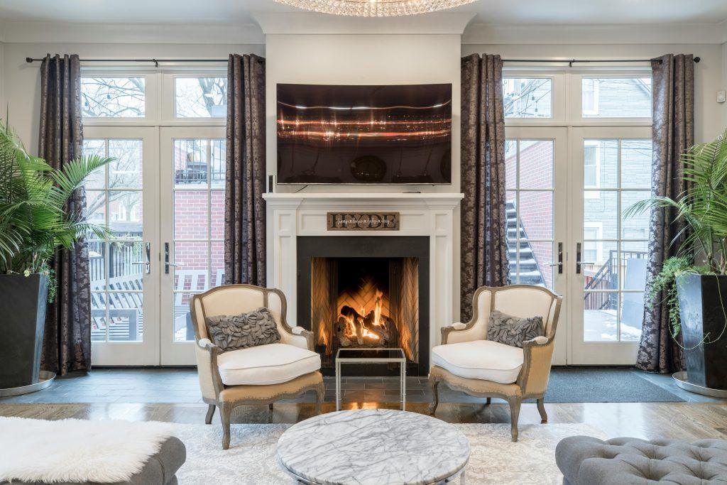 Una casa elegante con dos sillas y una chimenea encendida de fondo.