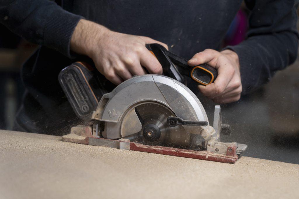 Una persona usando una de las herramientas más importantes para trabajar madera , la sierra eléctrica