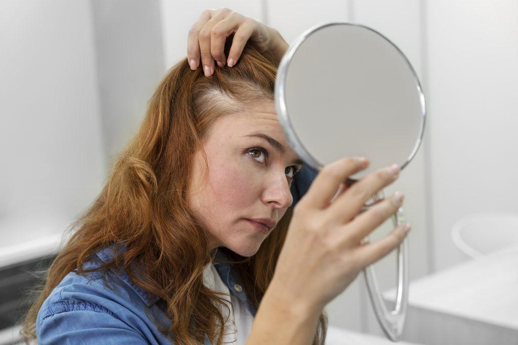 Una mujer revisando su pelo para ver resultados del mejor tratamiento para el pelo poroso con productos para usar en casa