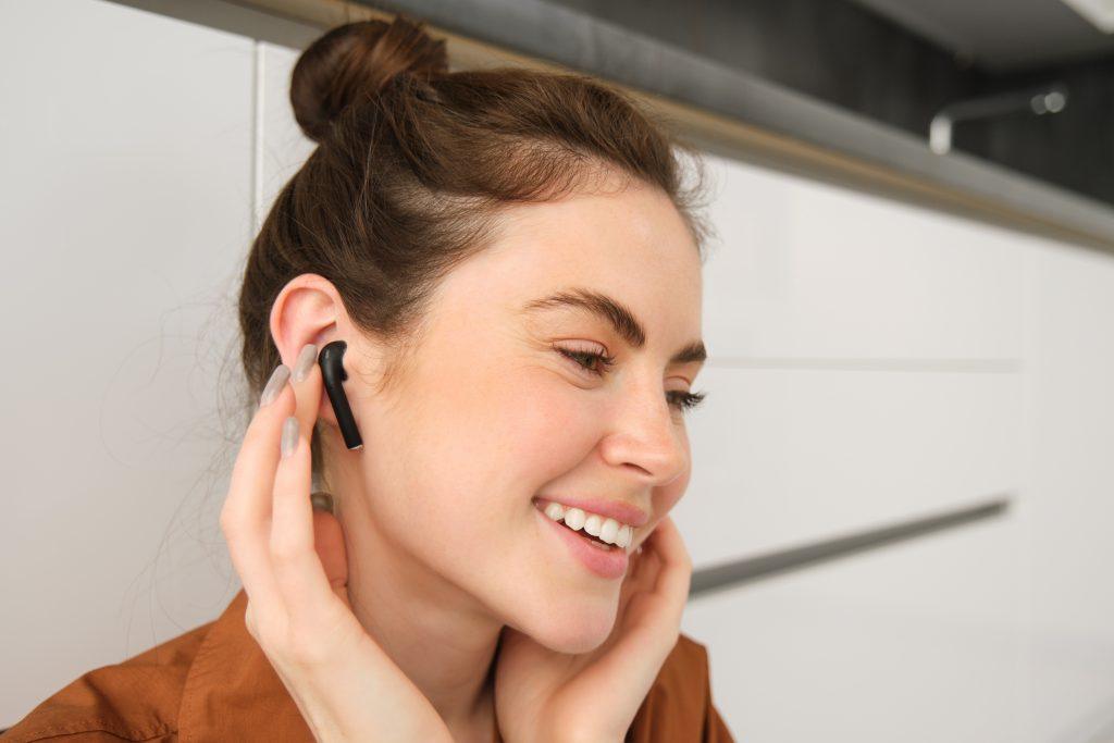 Una mujer escuchando un podcast con sus cascos bluetooth inalámbricos de teléfono móvil.