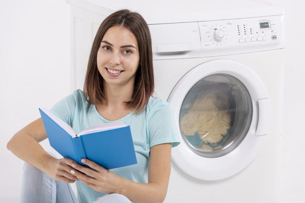 Una mujer leyendo un manual de una lavadora.