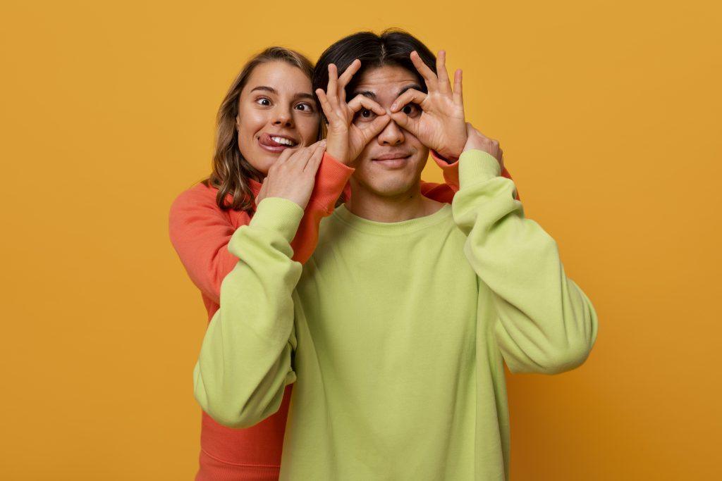 Dos personas, haciendo el tonto mientras leen frases para mejores amigos, con un fondo naranja.