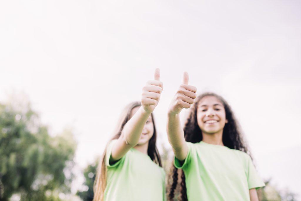 Dos mejores amigas sonriendo a la cámara con el pulgar arriba leyendo diferentes frases.