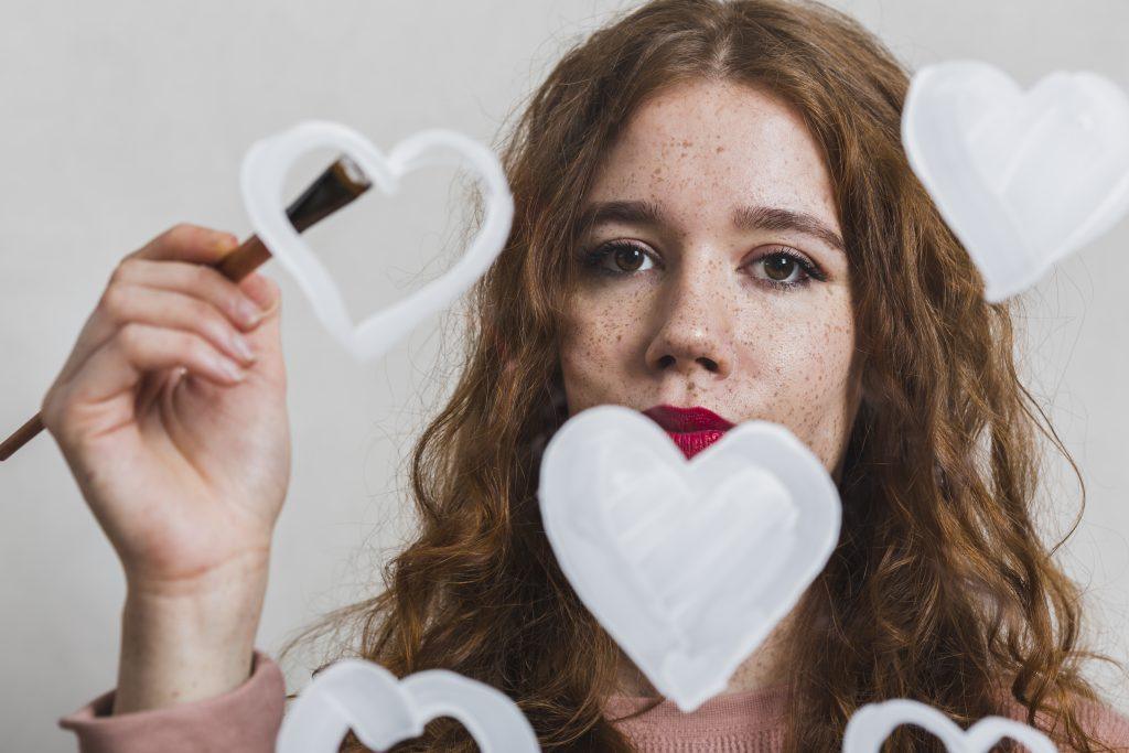 Una chica pintando corazones pesando en frases e indirectas para dedicarle a su narcisista.